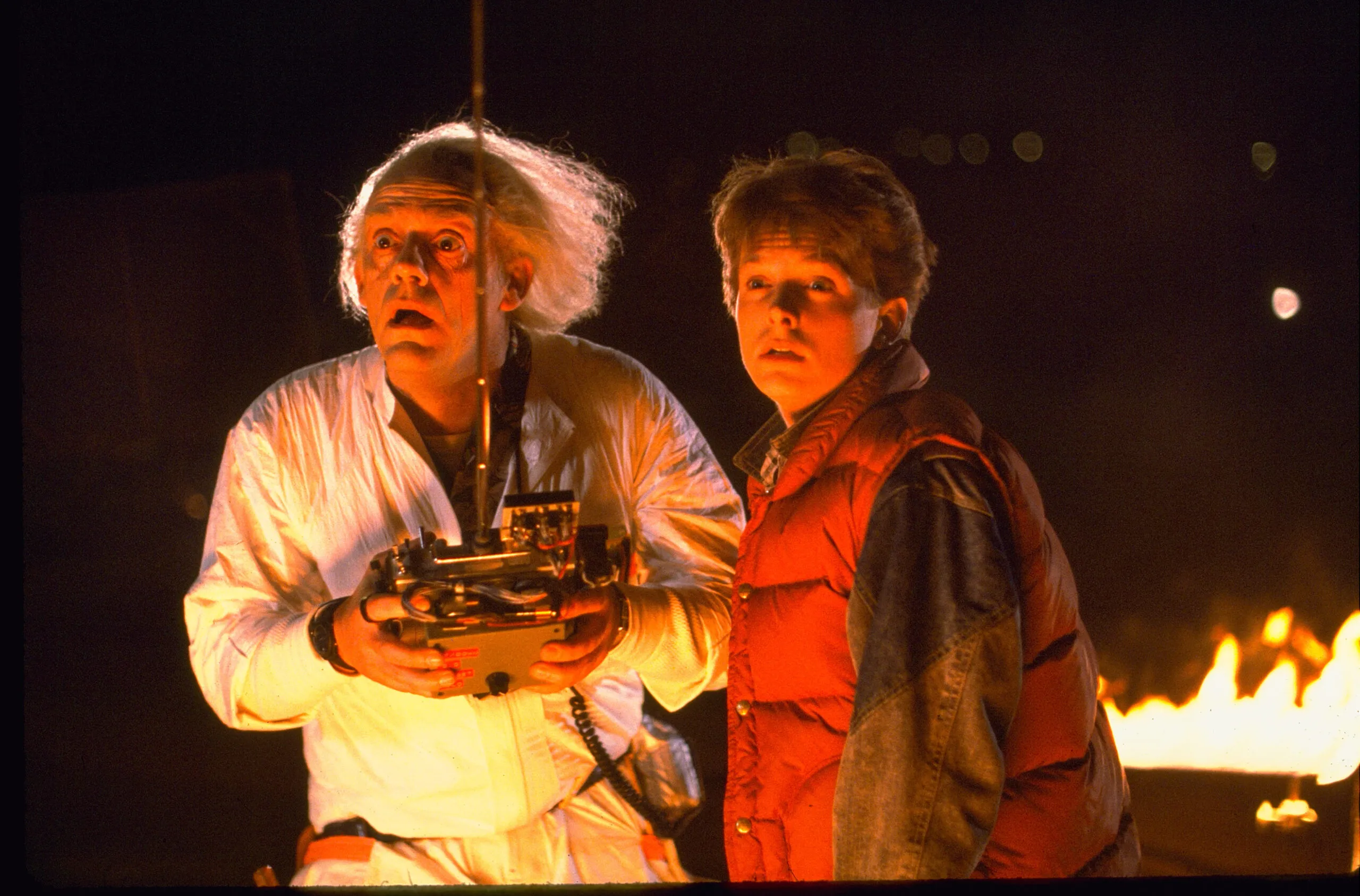 Marty McFly observando su reloj frente al DeLorean en el póster de "Volver al Futuro", clásico de ciencia ficción que cumple 40 años y regresa a los cines